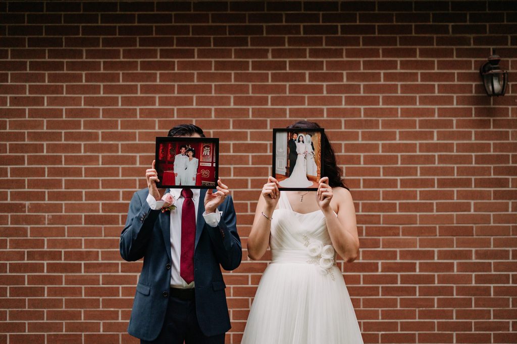Bride and groom holding up parent's wedding photos.